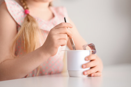 Cute little girl with yogurt at homeの写真素材