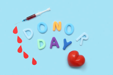 Composition with heart, paper drops, syringe and letters DONOR DAY on blue backgroundの写真素材