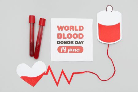 Composition with sign WORLD BLOOD DONOR DAY 14 JUNE and test tubes on gray background