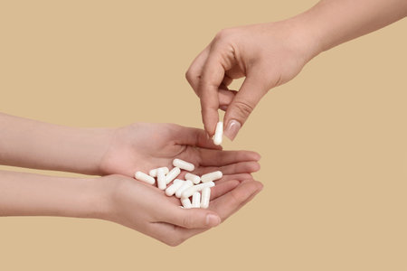 Female hands with pills on beige background