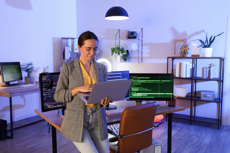 Beautiful programmer working with laptop in office at night
