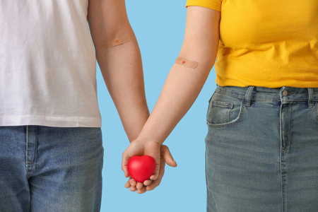 Blood donors with applied medical patches and heart on blue background