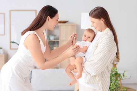 Young lesbian couple with their little baby at homeの写真素材