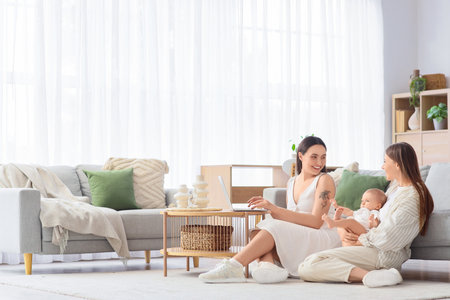 Young lesbian couple with their little baby using laptop at homeの写真素材