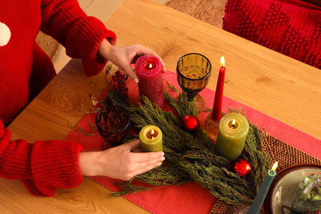 Young woman with burning candles at table in dining room on Christmas Eve, closeupの写真素材