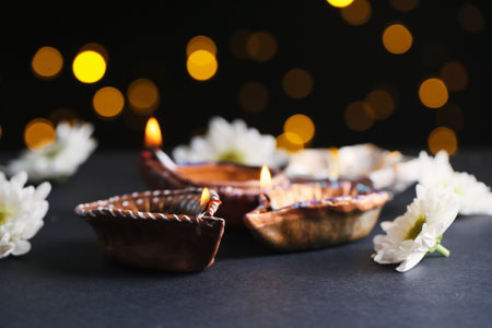 Diya lamps with flowers against blurred lights on black background. Divaly celebrationの写真素材