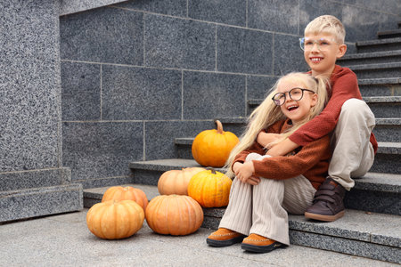 Happy children with pumpkins sitting on stairs outdoorsの写真素材