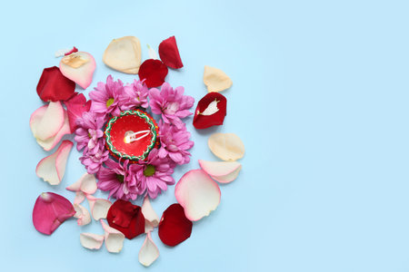 Diya lamp with flowers and rose petals on blue background. Divaly celebrationの写真素材