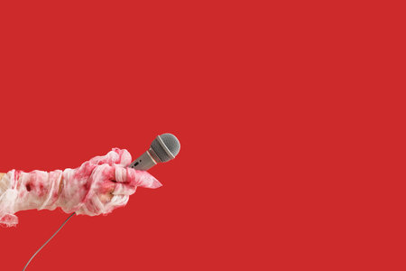 Mummy hands with microphone on red background. Halloween celebrationの写真素材