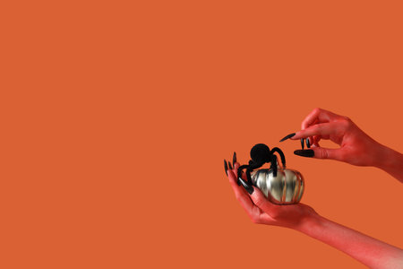 Devil hands with spider and pumpkin on orange background. Halloween celebrationの写真素材