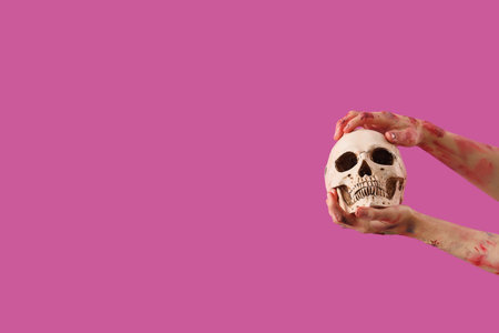 Zombie hands with human skull on pink background. Halloween celebrationの写真素材