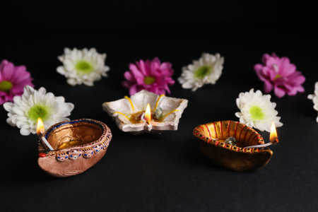 Diya lamps with flowers on black background. Divaly celebration