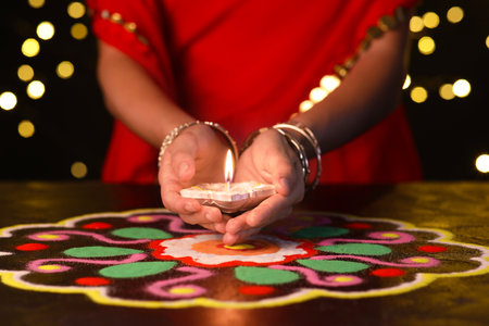 Woman holding diya lamp for Diwali on dark blurred backgroundの写真素材