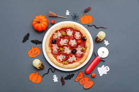 Composition with tasty Halloween pizza, cutter and different decorations on dark backgroundの写真素材