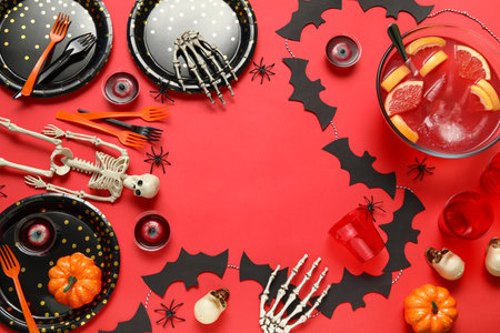 Frame made of decorations, tableware and tasty punch for Halloween party on red backgroundの写真素材