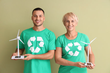 People in t-shirts with recycle signs and wind turbine models on green backgroundの写真素材