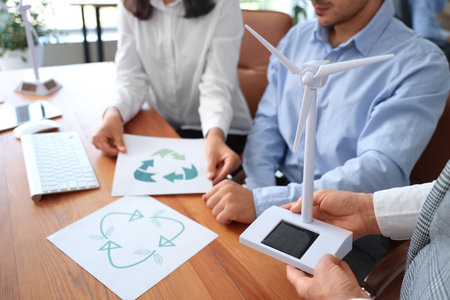 Engineers with wind turbine model and recycle signs in office, closeupの写真素材