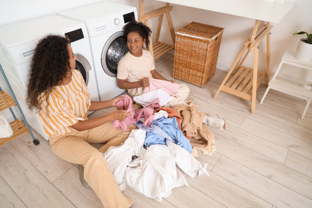 African-American woman and her daughter doing laundry at homeの写真素材