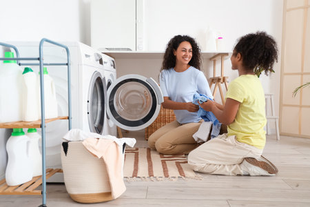 African-American woman and her daughter doing laundry at homeの写真素材