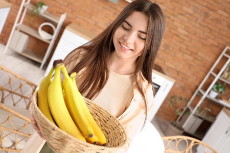 Young woman with bowl of bananas in kitchen, closeupの写真素材
