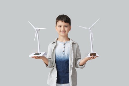 Cute little boy with wind turbine models on light backgroundの写真素材