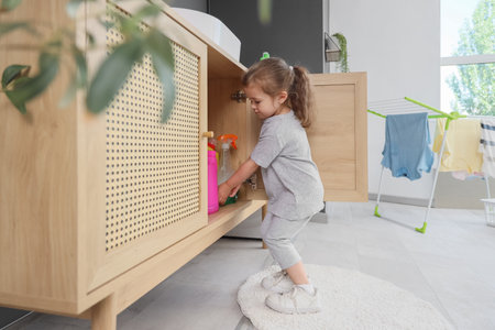 Cute little girl rummaging through drawer in laundry room. Child at riskの写真素材