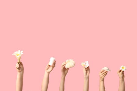 Female hands with flowers, spa stones, bath sponge and candle on pink backgroundの写真素材