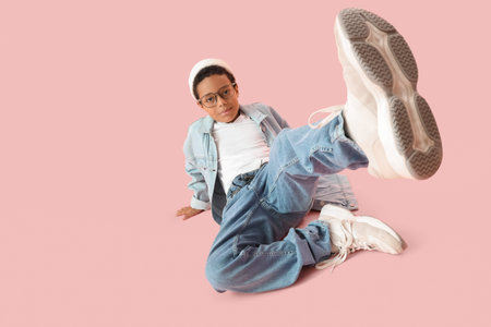 Little African-American boy in adult clothes on pink background