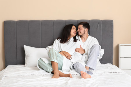 Happy young couple sitting in bedroomの写真素材
