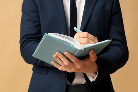 Young businessman with notebook on brown background, closeupの写真素材