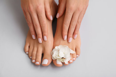 Female feet and hands with beautiful pedicure and manicure on light backgroundの写真素材