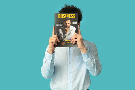 Young businessman with magazine on blue backgroundの写真素材
