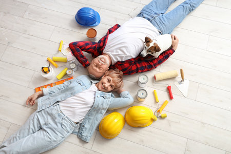 Mature couple with dog and repair tools lying on floor, top viewの写真素材