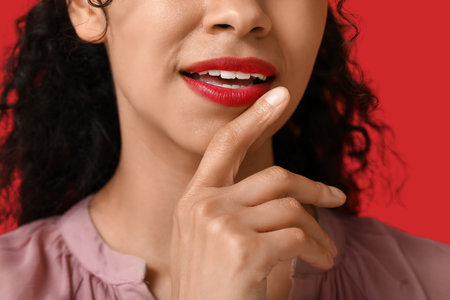 Young African-American woman with red lips on color background, closeupの写真素材