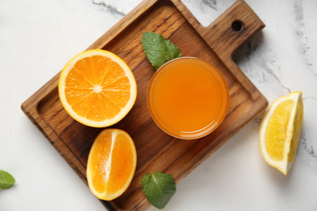 Glass of fresh orange juice with mint and cut fruit on white backgroundの写真素材