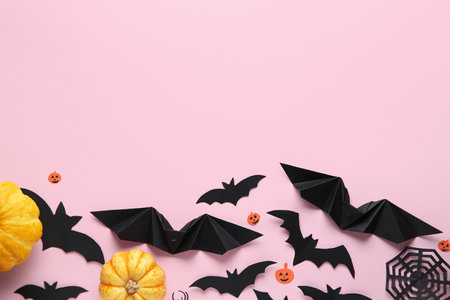 Paper bats with spider web and fresh pumpkins for Halloween party on pink backgroundの写真素材