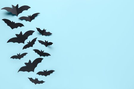 Many black paper bats for Halloween party on blue background