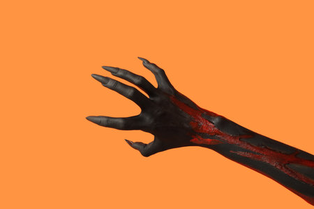Black witch hand with claws on orange background. Halloween celebrationの写真素材