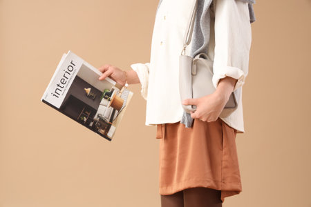 Young woman with magazine on brown background, closeupの写真素材