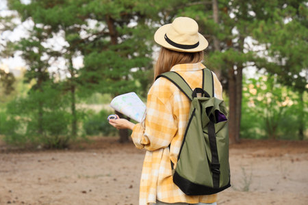 Female traveler with compass and map in forest, back viewの写真素材