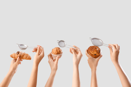 Female hands with sieves and different tasty pastry on gray backgroundの写真素材