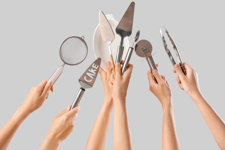Female hands holding different baking utensils on gray backgroundの写真素材