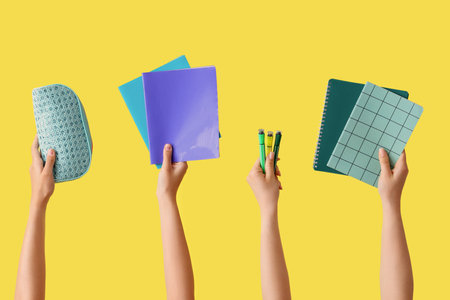 Female hands with school supplies and felt-tip pens on yellow backgroundの写真素材