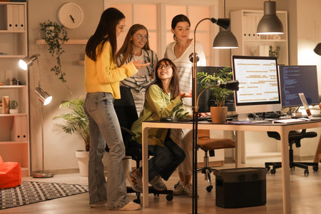 Team of female programmers working in office at night