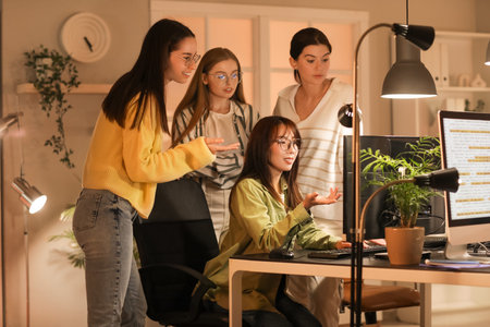 Team of female programmers working in office at night