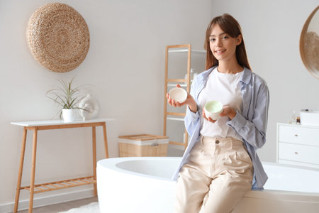 Morning of young woman with jar of cream in bathroom