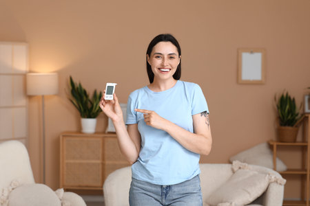 Diabetic young woman pointing at glucometer in room