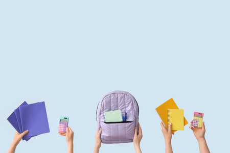 Female hands with set of school equipment and backpack on blue backgroundの写真素材