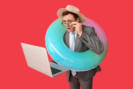 Office worker with inflatable ring using laptop on red background