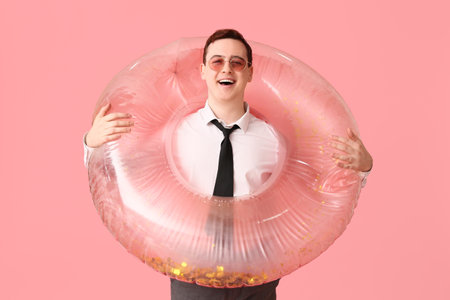 Office worker with inflatable ring dreaming about vacation on pink backgroundの写真素材